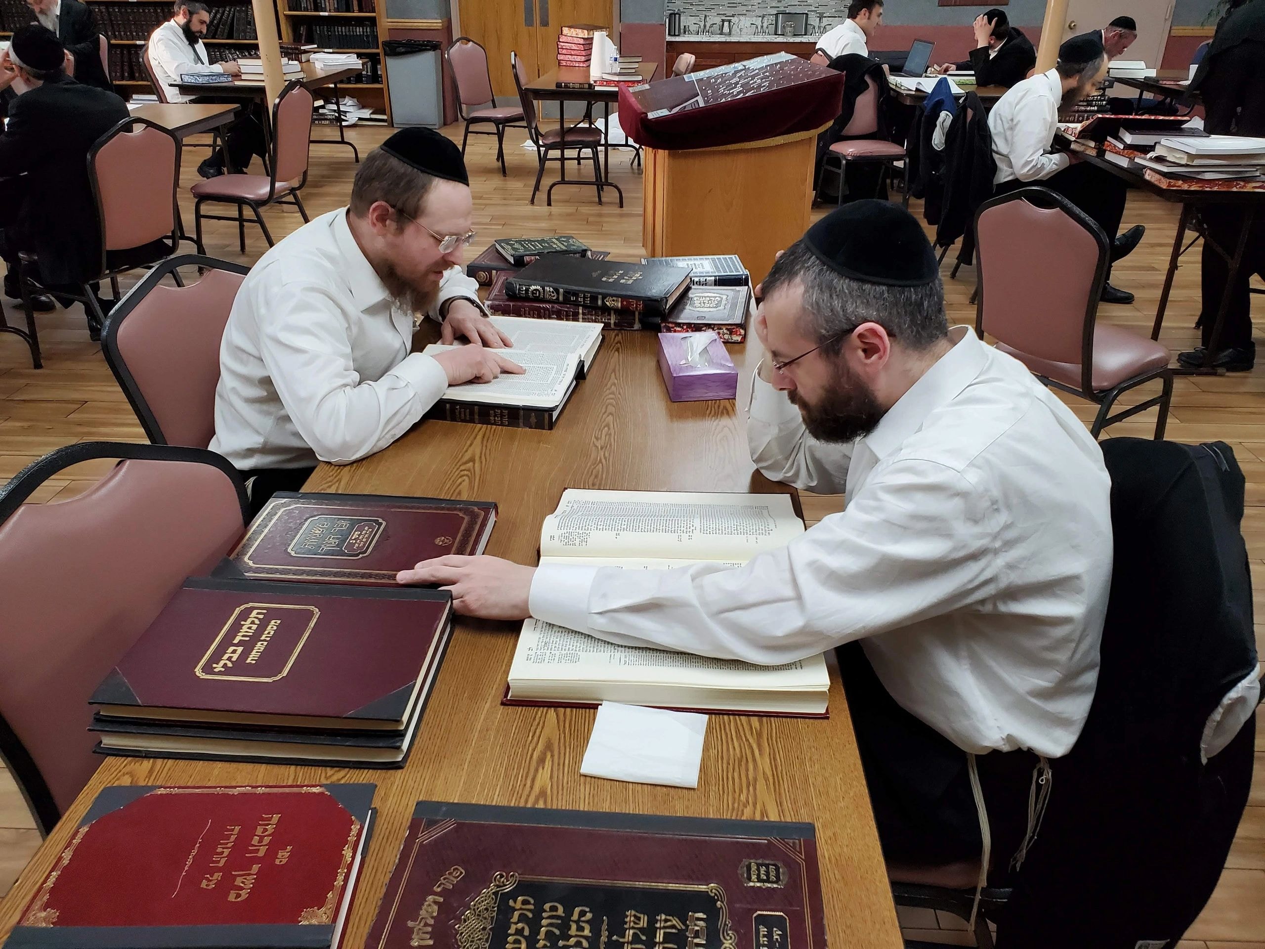 Kollel study hall with men learning religious texts