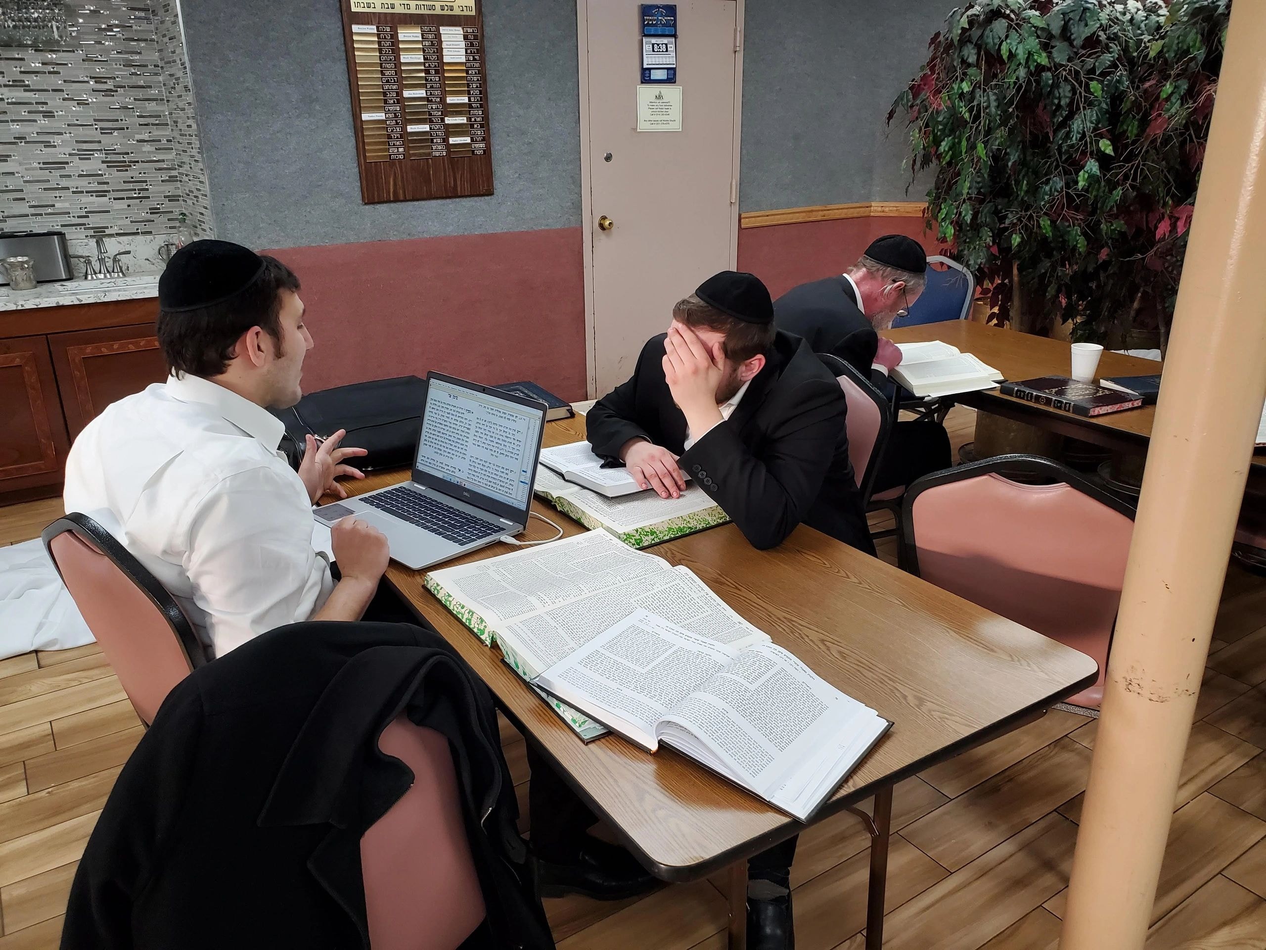 Orthodox Jewish men studying with open books and laptop