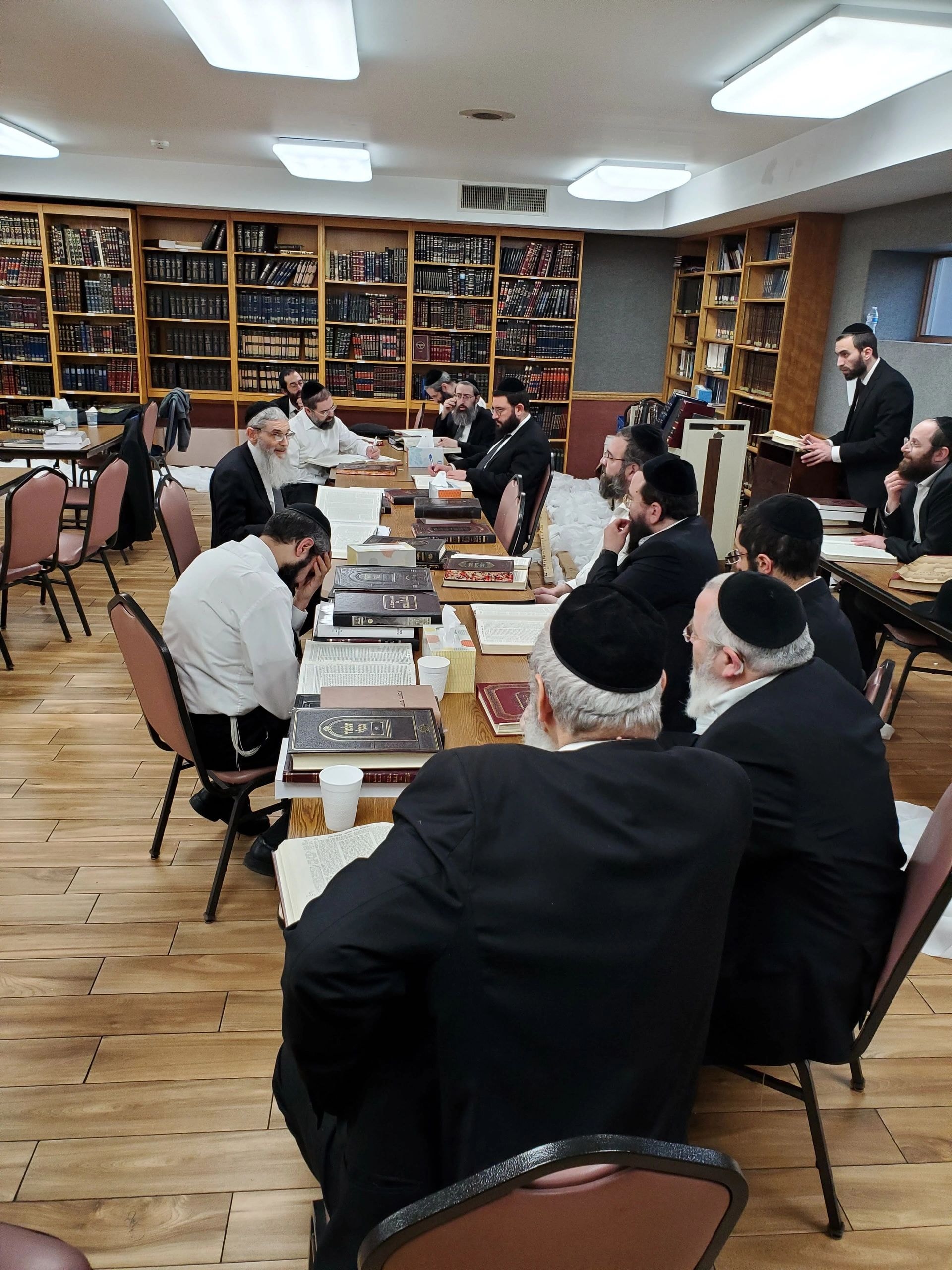 Group of men in black suits gathered in library study room